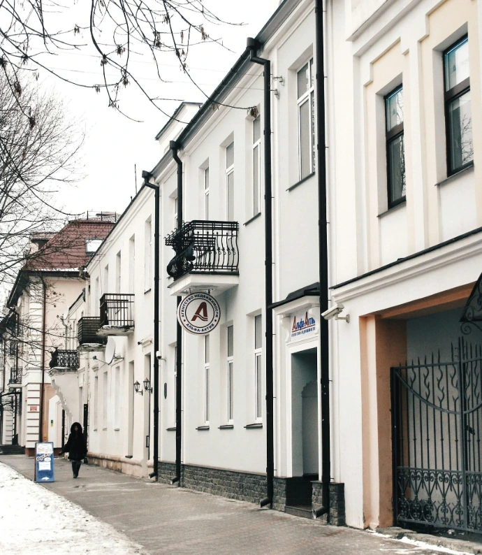A person walks down a snowy street lined with buildings.